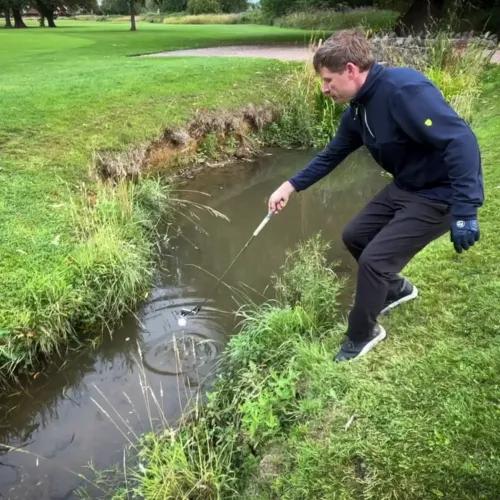 Golfer scooping a ball from water using ClubScoop